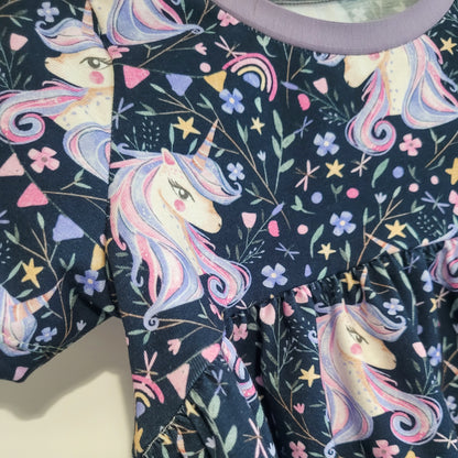 Close-up of unicorn fabric showing sleeve and bodice detail on handmade children’s peplum top